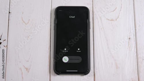 A close-up of an incoming call from the chef on a mobile phone screen on a light wooden background. 