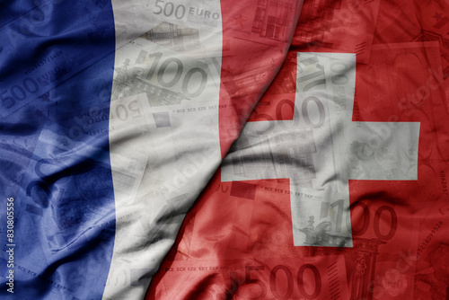 big waving realistic national colorful flag of switzerland and national flag of france on a euro money banknotes background. photo