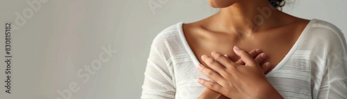 Close-up of a woman's hands placed over her heart, symbolizing gratitude, gratitude, well-being, and self-care, captured in a soft, warm light.