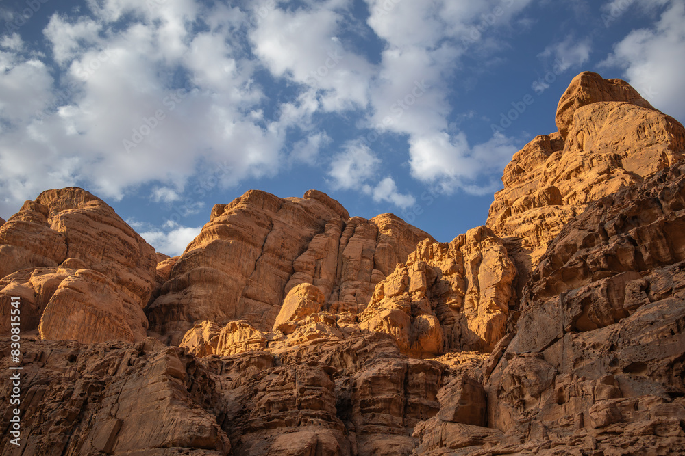 Rock Formation of Sandstone Stone with Blue Sky and Clouds during Golden Hour in Wadi Rum. Beautiful Geological Outdoor View in Southern Jordan.