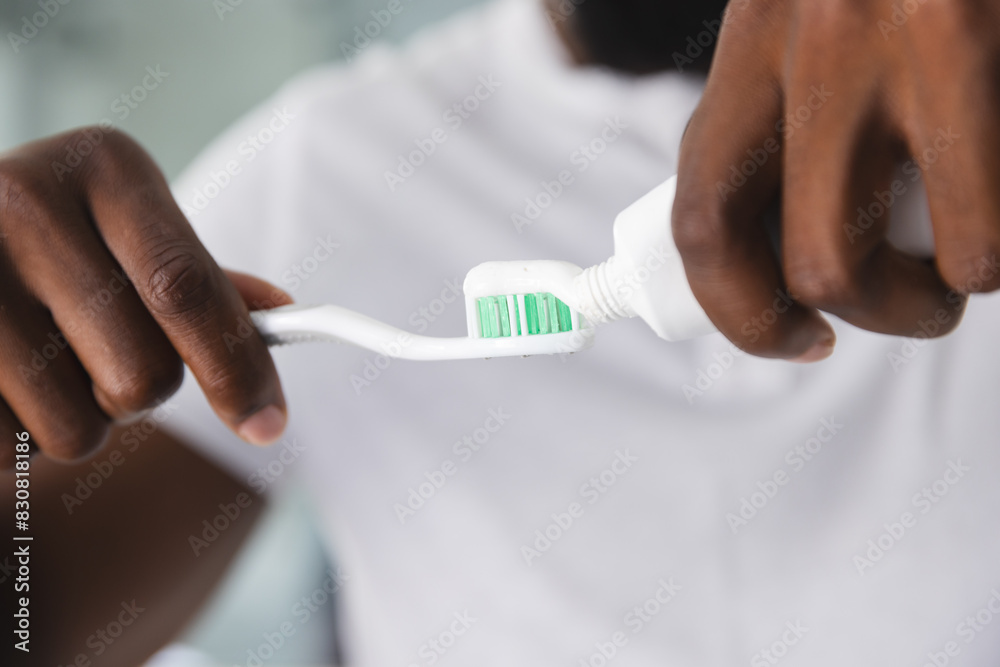 At home, African American man applying toothpaste on toothbrush At home, African American man applying toothpaste on toothbrush