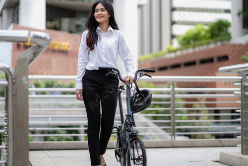 Smart businesswoman ride bicycle in downtown. Environmentalist commuting by cycling reduce carbon footprint global warming. Bike to work eco friendly alternative transportation green energy vehicle © Nassorn