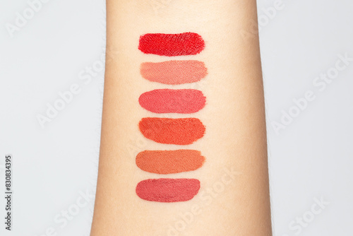 Lipstick swatches on arm woman isolated in bright background. Test cosmetic color shade beauty and fashion concept.