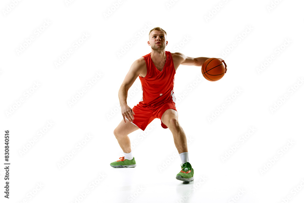 Young athletic man, professional basketball player dressed red uniform ready to score goal against white studio background. Concept of professional sport, games, healthy lifestyle, tournament, action.