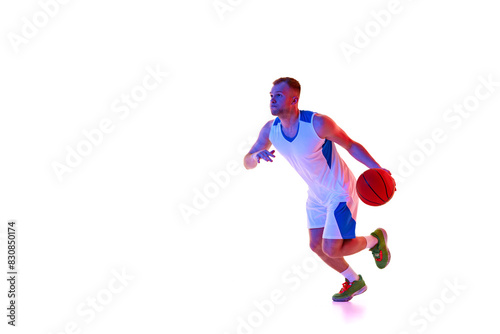 Young man, basketball player running in motion take perfect shot in neon light against white studio background. Concept of professional sport, games, healthy lifestyle, tournament, action. Ad