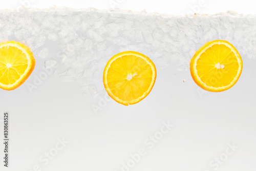 Textured photo. Slices of citrus, sweet and sour orange float in clear water with ice cubes against white background. Abstract wallpaper. Concept of food and drinks, summer,vitamins, nutrition. photo