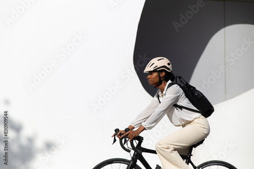 Businesswoman cycling bicycle by white building photo