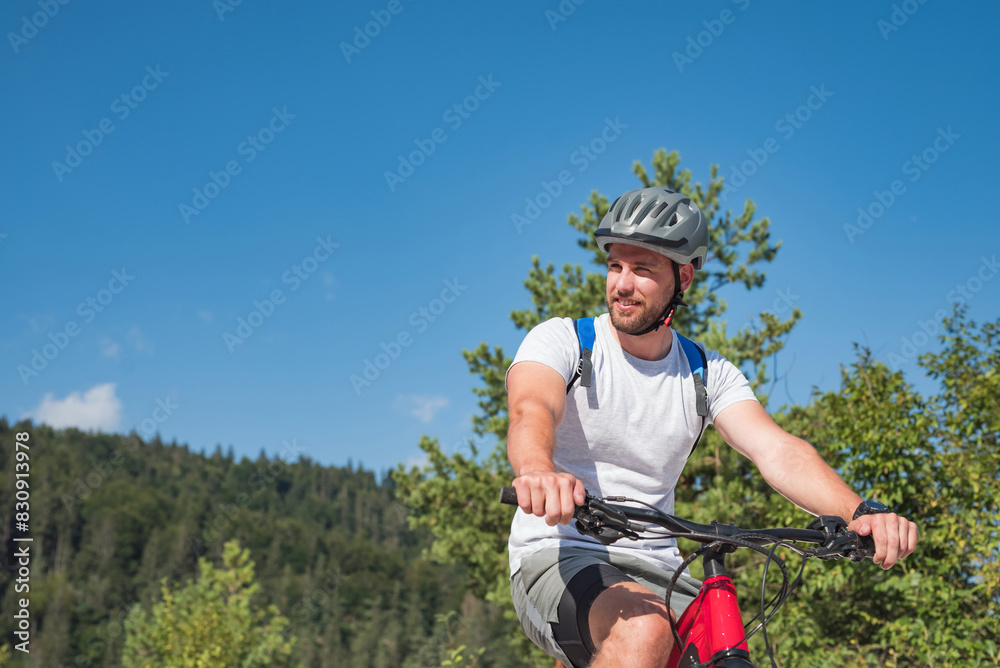 Mountain bike rider riding an electric bike along a white gravel trail on a sunny summer day. Outdoor sports activity concept. Mountain bike rider riding an electric bike along a white gravel trail on a sunny summer day. Outdoor sports activity concept.