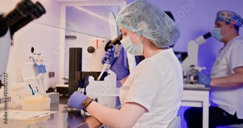 Embryologist in a laboratory carefully performing artificial fertilization of a human egg using specialized equipment. Displays a high-tech lab environment focused on reproductive science and IVF.