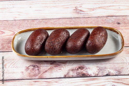 Gulab Jamun, kalo jam or mohan served in tray dish isolated on wooden table side view of indian, pakistani and bangladeshi sweet food photo