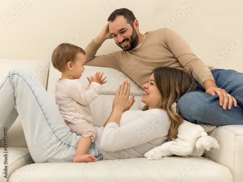 Mother and daughter play with each other while the father looks at them smiling