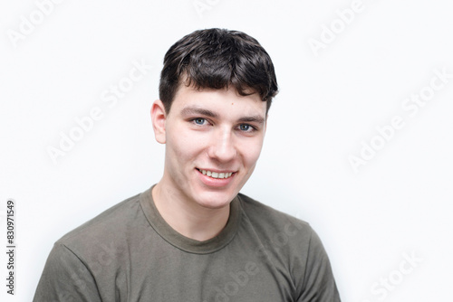 Active guy, college student, smiling happily on light background, boy is successfully graduating from college, dreams of successful career. Portrait of happy positive guy 19 years old smiling