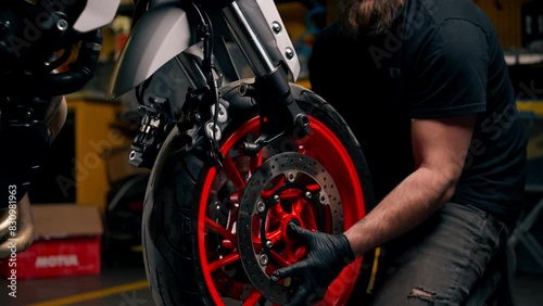 close up In a motorcycle repair shop mechanic removes the front wheel and rolls it back to replace the tires