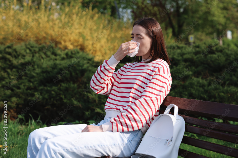 Woman with napkin suffering from seasonal allergy on bench in park Woman with napkin suffering from seasonal allergy on bench in park