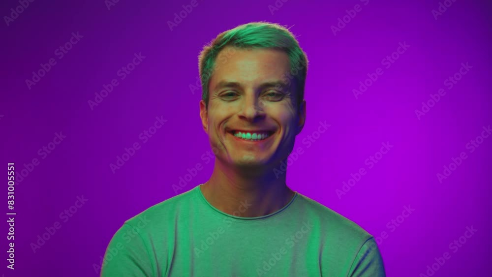 Happy Portrait of Adult Man Looking at Camera and Smiling in Neon Colored Lights. Close Up View on Mature Person with Good Mood and White Teeth Grin. Cool Modeling Pose in Vivid Playful Shoot Indoors Happy Portrait of Adult Man Looking at Camera and Smiling in Neon Colored Lights. Close Up View on Mature Person with Good Mood and White Teeth Grin. Cool Modeling Pose in Vivid Playful Shoot Indoors