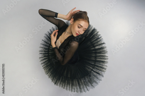 portrait of a young ballerina in a black tutu dancing with her hands moving top view, immersion in dance