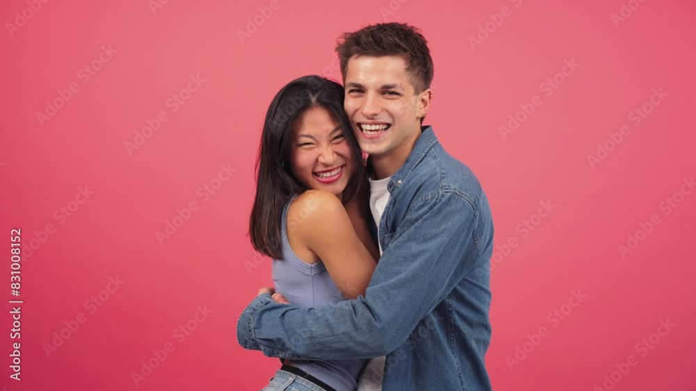 Young adult multiracial couple smiling and hugging in front of a red color studio background. Two people in a romantic and happy pose looking at the camera together. Lovely boyfriend and girlfriend Young adult multiracial couple smiling and hugging in front of a red color studio background. Two people in a romantic and happy pose looking at the camera together. Lovely boyfriend and girlfriend