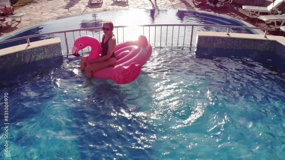 Aerial drone view of woman on pink flamingo pool float in pool in hotel. Summer holidays, enjoying summer vacations footage from above
