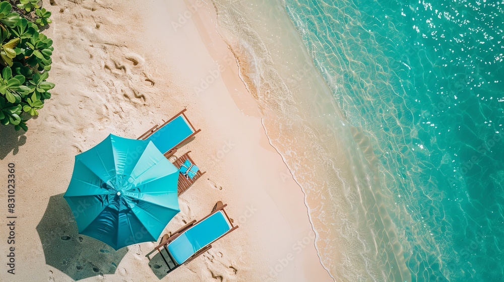 Naklejka premium Tropical vacation background. Sun lounger with umbrella and beach accessories for active rest on the sandy island, copy space, top view