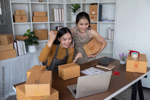 Happy female entrepreneurs celebrating online sales success in home office. Concept of small business, ecommerce, and teamwork © Natee Meepian