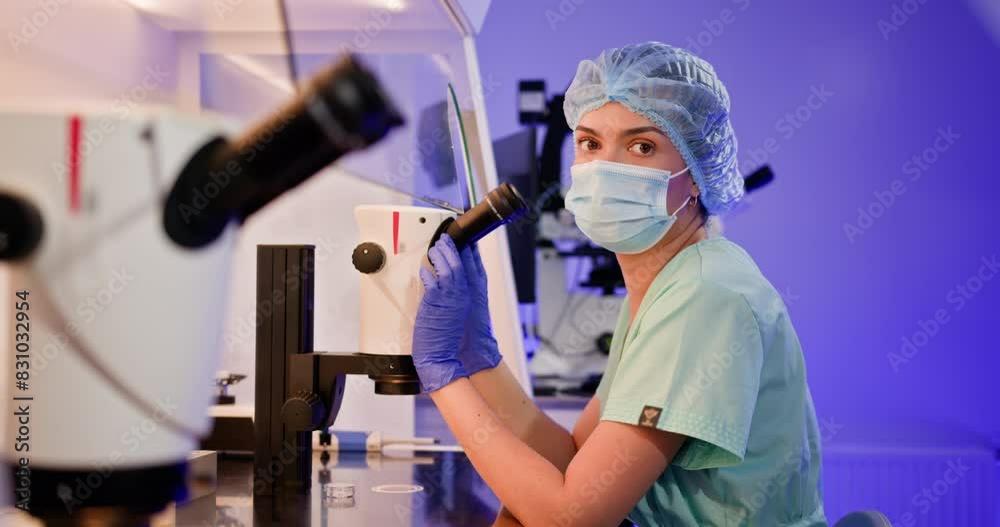 A dedicated embryologist performing artificial fertilization. Portrait of research student scientist. Portrait of female black scientist in protective wear looking under microscope does analysis