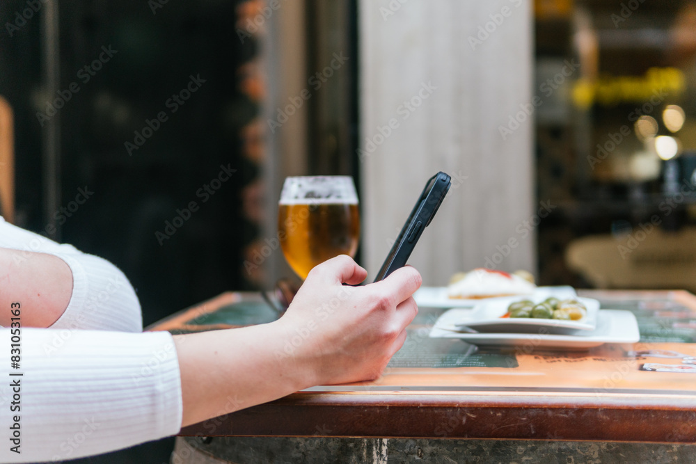 Fototapeta premium Person is taking a photo of their meal and beer with a smartphone at a restaurant