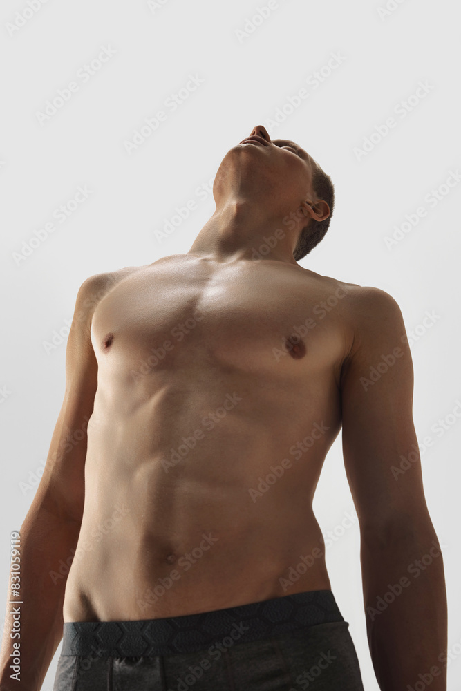 Fototapeta premium Bottom view image if shirtless young man with athletic, sportive body shape isolated on white studio background. Concept of male beauty, body care, fitness, sport, health, wellness