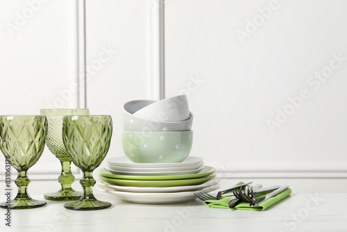 Beautiful ceramic dishware  glasses and cutlery on white marble table. Space for text