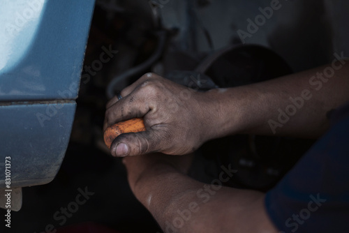 Close up Mechanic man hands repairing car auto repair shop uses jack change tyre. Man hands fixing Shock absorber machinery vehicle mechanical service. Vehicle Car overhaul maintenance engineer