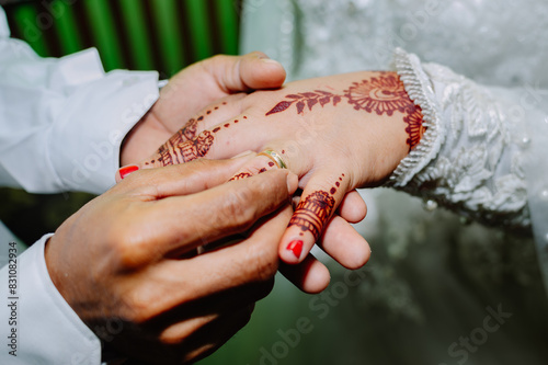 the groom puts a wedding ring on the bride's ring finger as a sign that they are officially married together photo