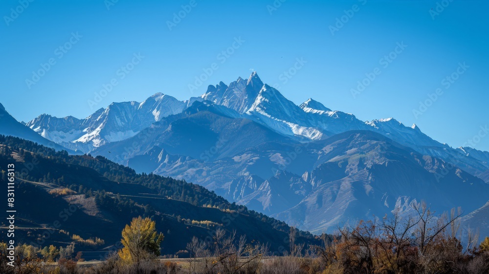 In the background, the towering mountains stood majestically against the clear blue sky, their peaks dusted with snow, creating a breathtaking contrast.