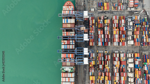 Photography top down view from drone, crane lift container into the transport ship in commer