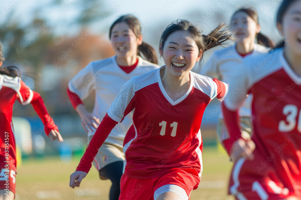 Obraz premium A team of cheerful Japanese female soccer players eagerly engage in a playful game, each aiming to strike the ball with precision and skill.