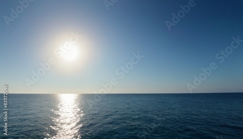 The gentle sunrise over a calm ocean horizon offers a tranquil scene with the sun reflecting off the water s surface.