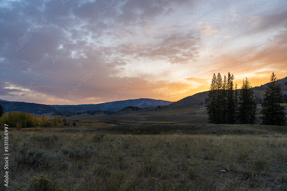 Obraz premium Sunset in the Lamar Valley in Yellowstone National Park in Montana and Wyoming on a beautiful fall evening. Sun sets over the mountains and sagebrush with a colorful sky illuminating the landscape.