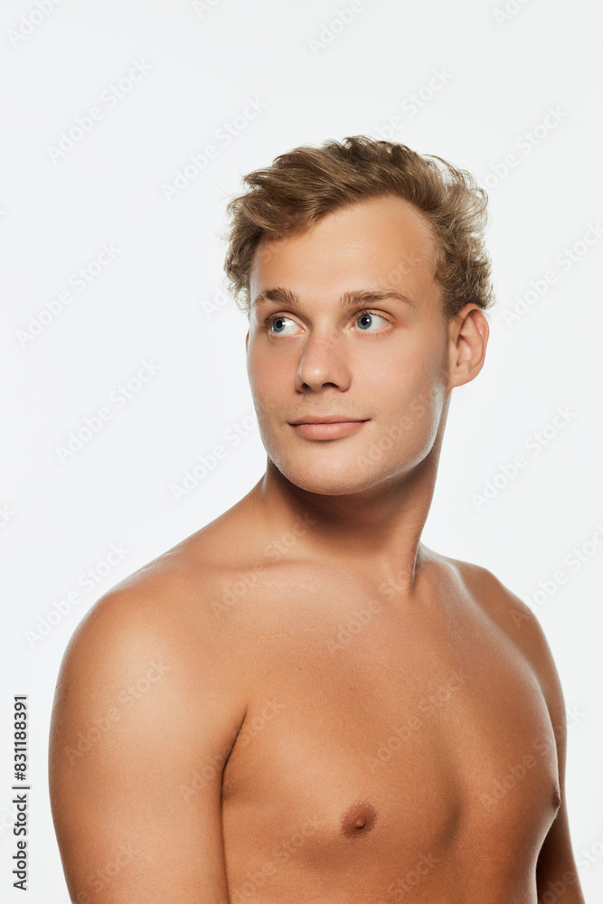 Portrait of young attractive man with athletic man posing shirtless and looking away against white background. Concept of male health, beauty and self care, youth, body and skin care. Portrait of young attractive man with athletic man posing shirtless and looking away against white background. Concept of male health, beauty and self care, youth, body and skin care.