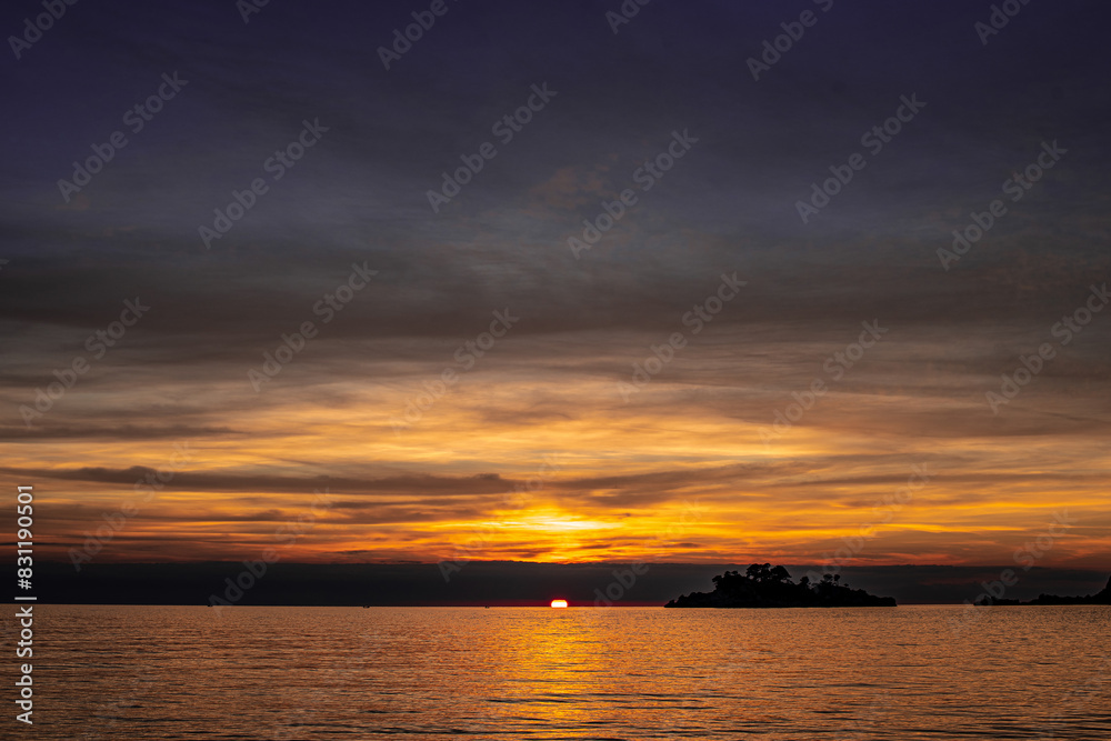 sunset over the sea with bright sun and dark clouds