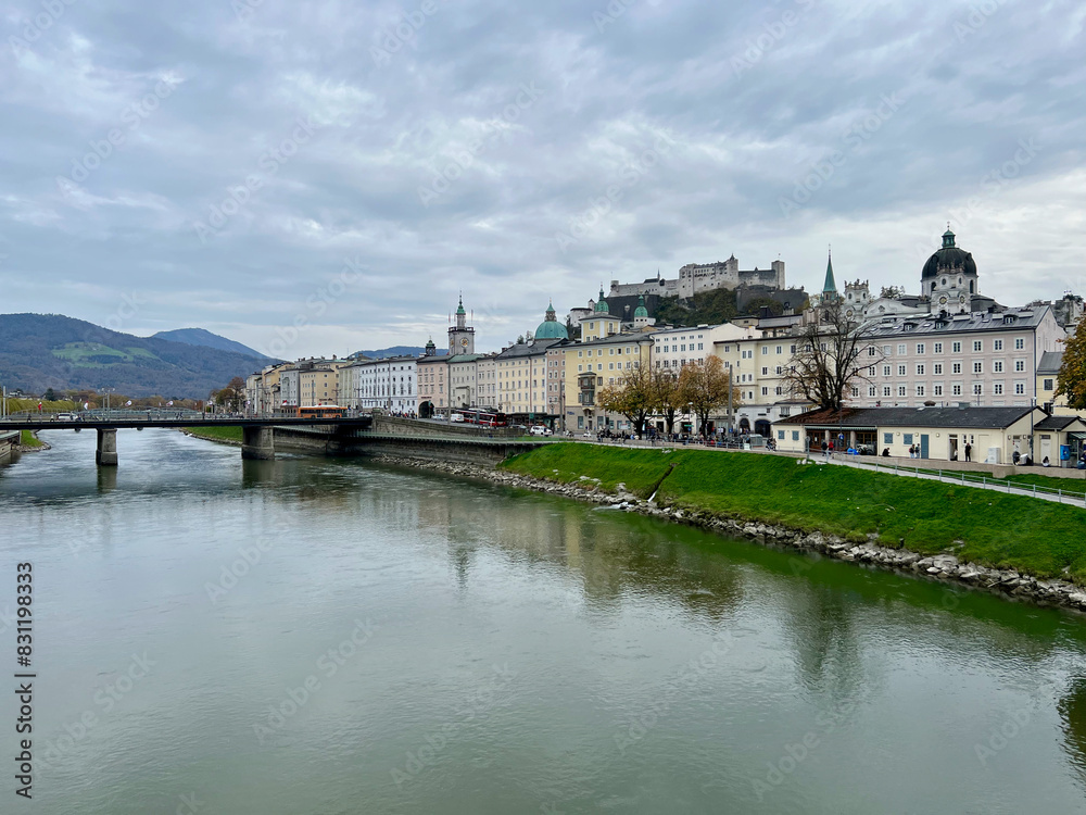 Fototapeta premium Marko-Feingold-Steg bridge above the Salzach River in Salzburg, Austria, showcasing its modern design and scenic surroundings with the city in the background.