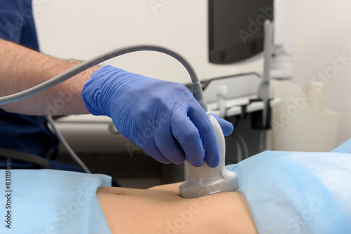 A doctor using an ultrasound transducer performs an ultrasound examination. Ultrasound scanner on a woman’s stomach, ultrasound of internal organs and abdominal cavity. Elastography and sonography.