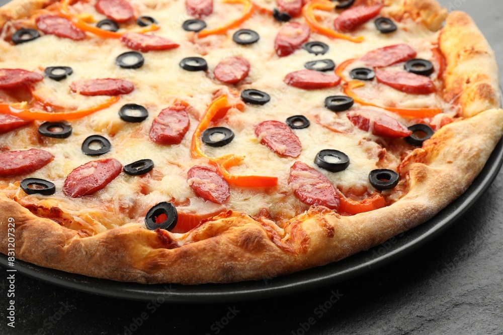 Tasty pizza with cheese, dry smoked sausages, olives and pepper on grey table, closeup Tasty pizza with cheese, dry smoked sausages, olives and pepper on grey table, closeup