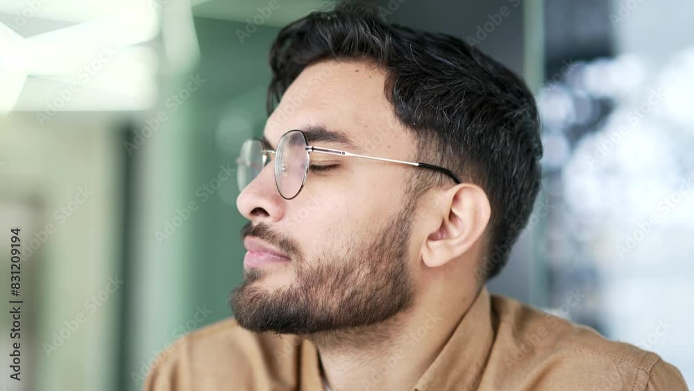Thoughtful serious entrepreneur thinks about solving a problem, sitting at workplace in business office. Portrait of a focused bearded businessman. Headshot of a manager or worker in glasses. Close up