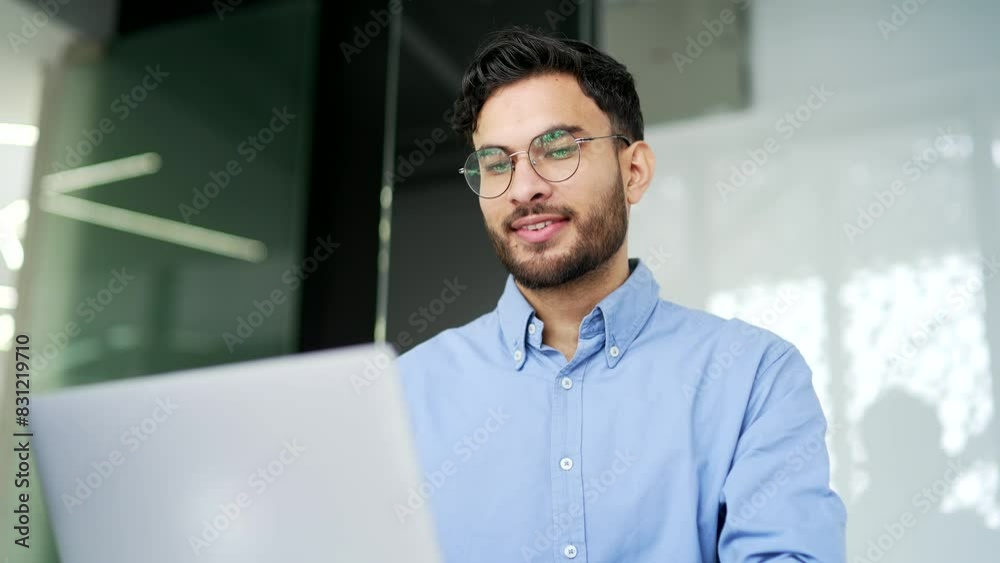 Worker in glasses working on a laptop sitting at workplace in business office. Happy man employee using computer application, banking, texting a client, chatting online. busy with a project. Close up