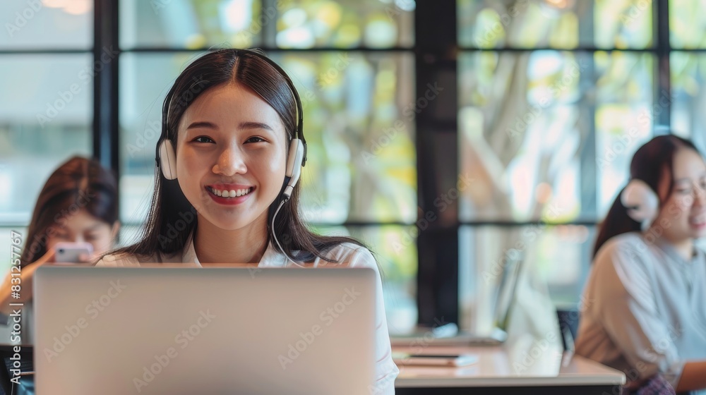 A smiling businesswoman with headset sitting in office and working on laptop, Costumer service, Support staff, Call center A smiling businesswoman with headset sitting in office and working on laptop, Costumer service, Support staff, Call center