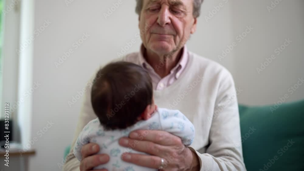 Back view of an elderly man holding a newborn baby, both in a calm and serene home setting, emphasizing the gentle and tender care given to the infant, with soft light streaming in