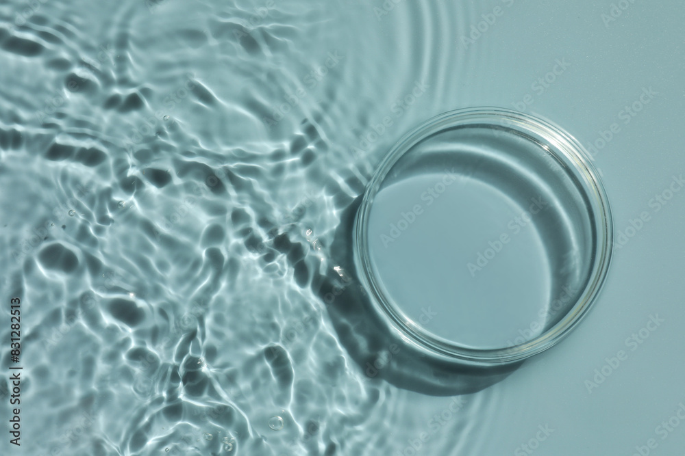 Stylish presentation for product. Glass podium in water on light blue background, top view. Space for text Stylish presentation for product. Glass podium in water on light blue background, top view. Space for text