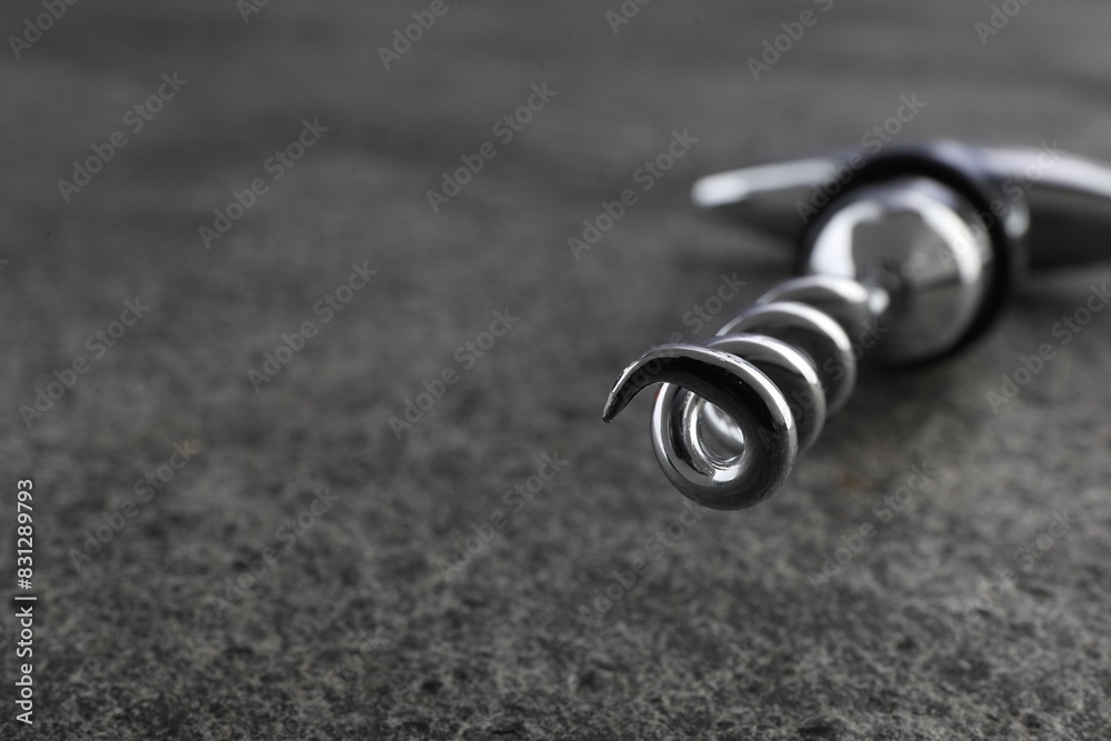 One metal corkscrew on grey textured table, closeup. Space for text One metal corkscrew on grey textured table, closeup. Space for text