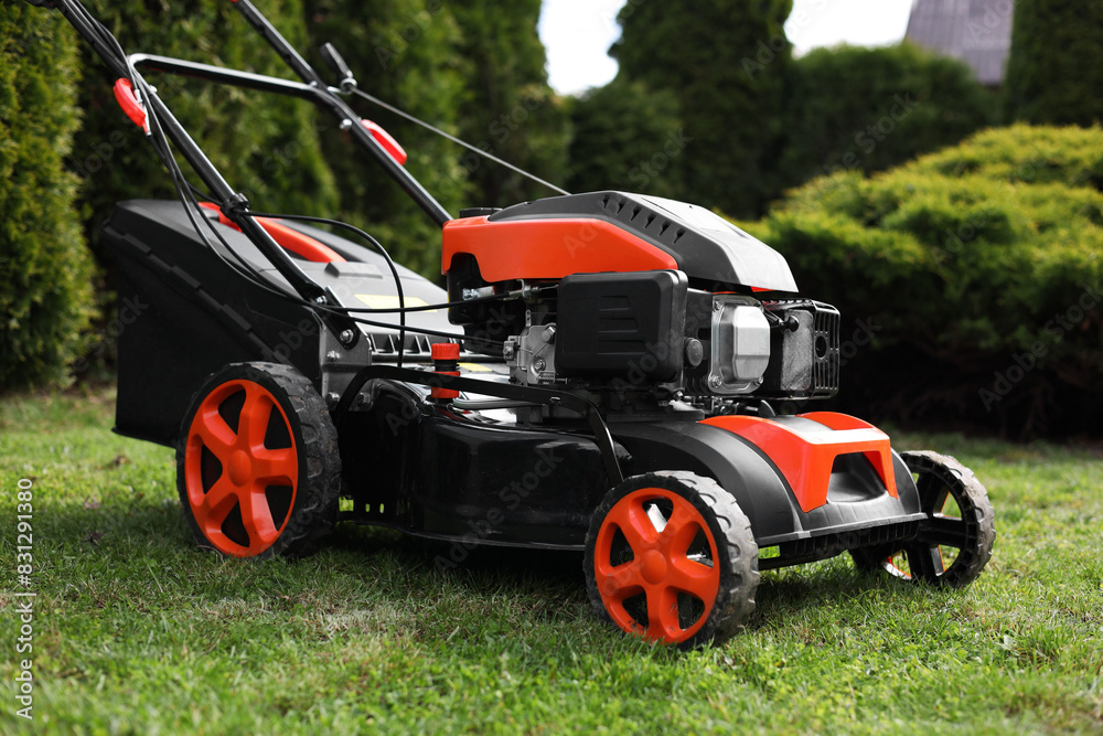 Obraz premium Modern lawn mower on green grass in garden