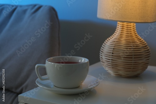 Obraz na plátně Cup of hot tea and nightlight on white table at night