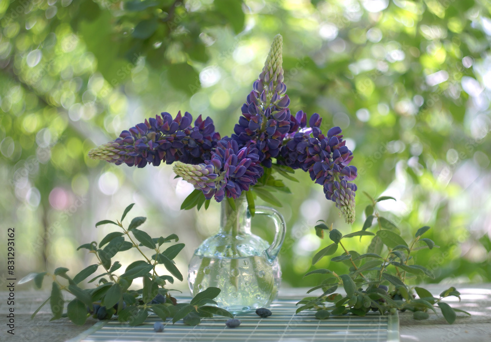 Φωτογραφία bouquet of fresh purple lupines in a glass bottle on a blurred background of a t