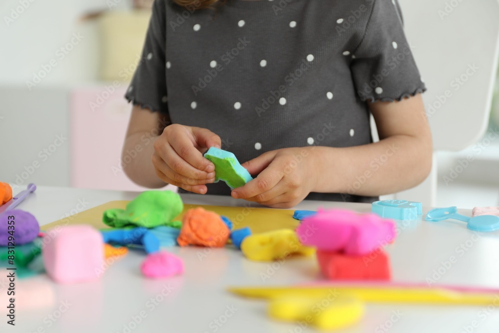 Little girl sculpting with play dough at table indoors, closeup Little girl sculpting with play dough at table indoors, closeup